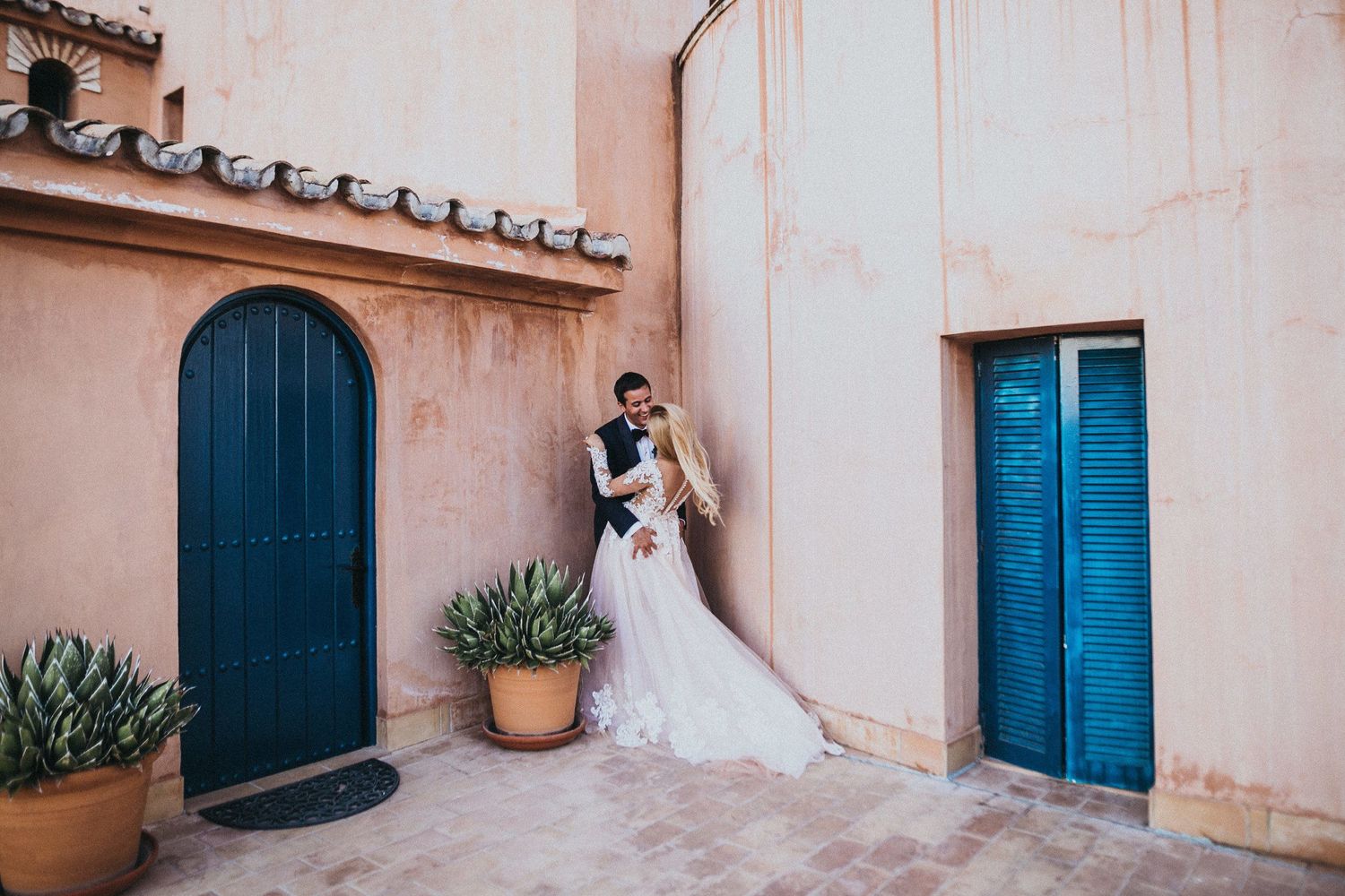 Wedding couple posing between blue doors on a Mediterranean style terrace.