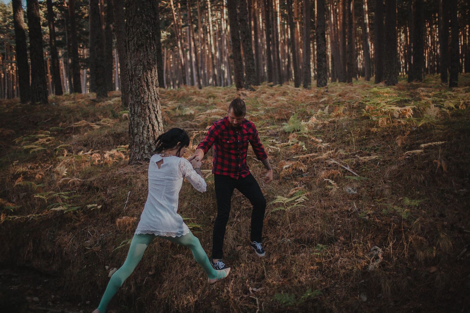 Playful moment between couple running through autumn forest setting.