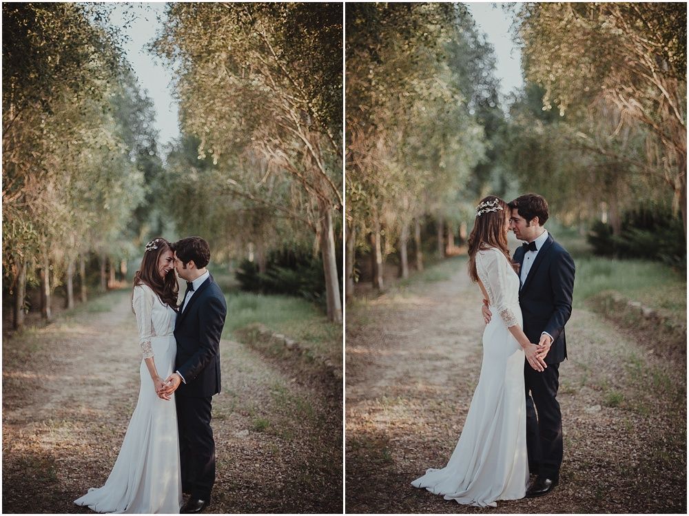 A romantic outdoor wedding photo shoot on a tree-lined dirt path at dusk.
