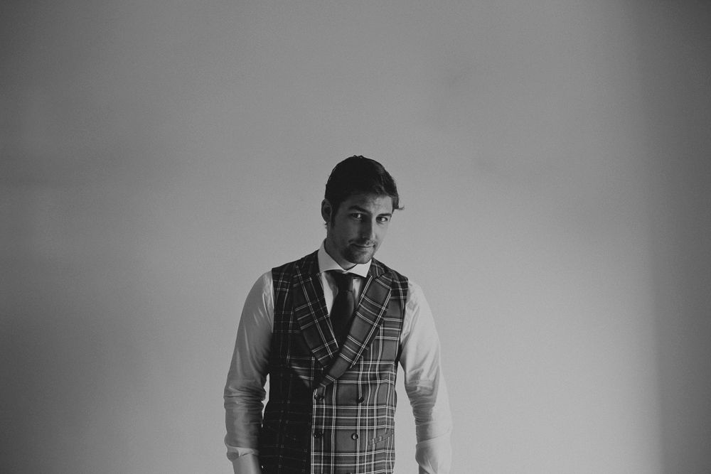 Side view of person in plaid vest and white dress shirt against gray background.