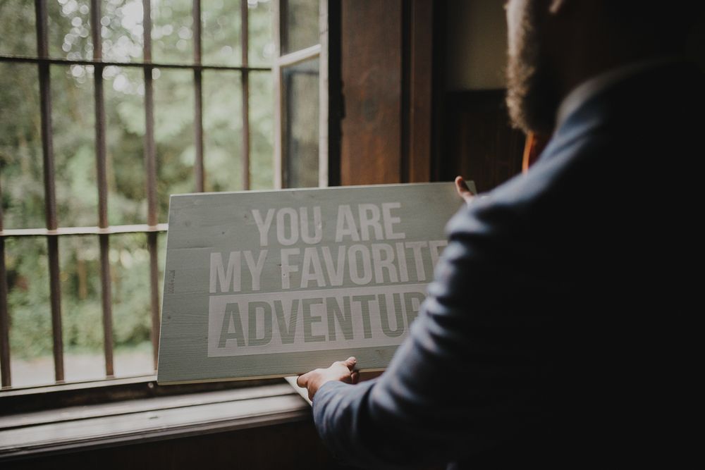Sign reading 'You are my favorite adventure' on windowsill with figure in blue jacket.