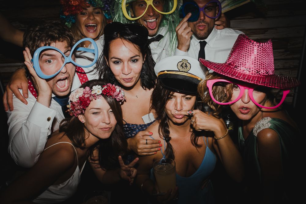 Party guests wearing colorful accessories and props posing together for fun group photo.