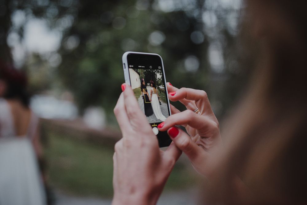 Hand holding smartphone taking photo at outdoor event.