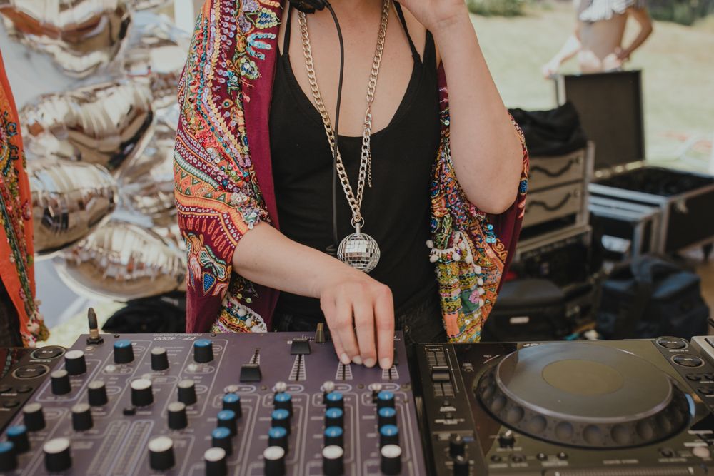 Close-up of DJ mixing at turntables wearing black top and patterned kimono.