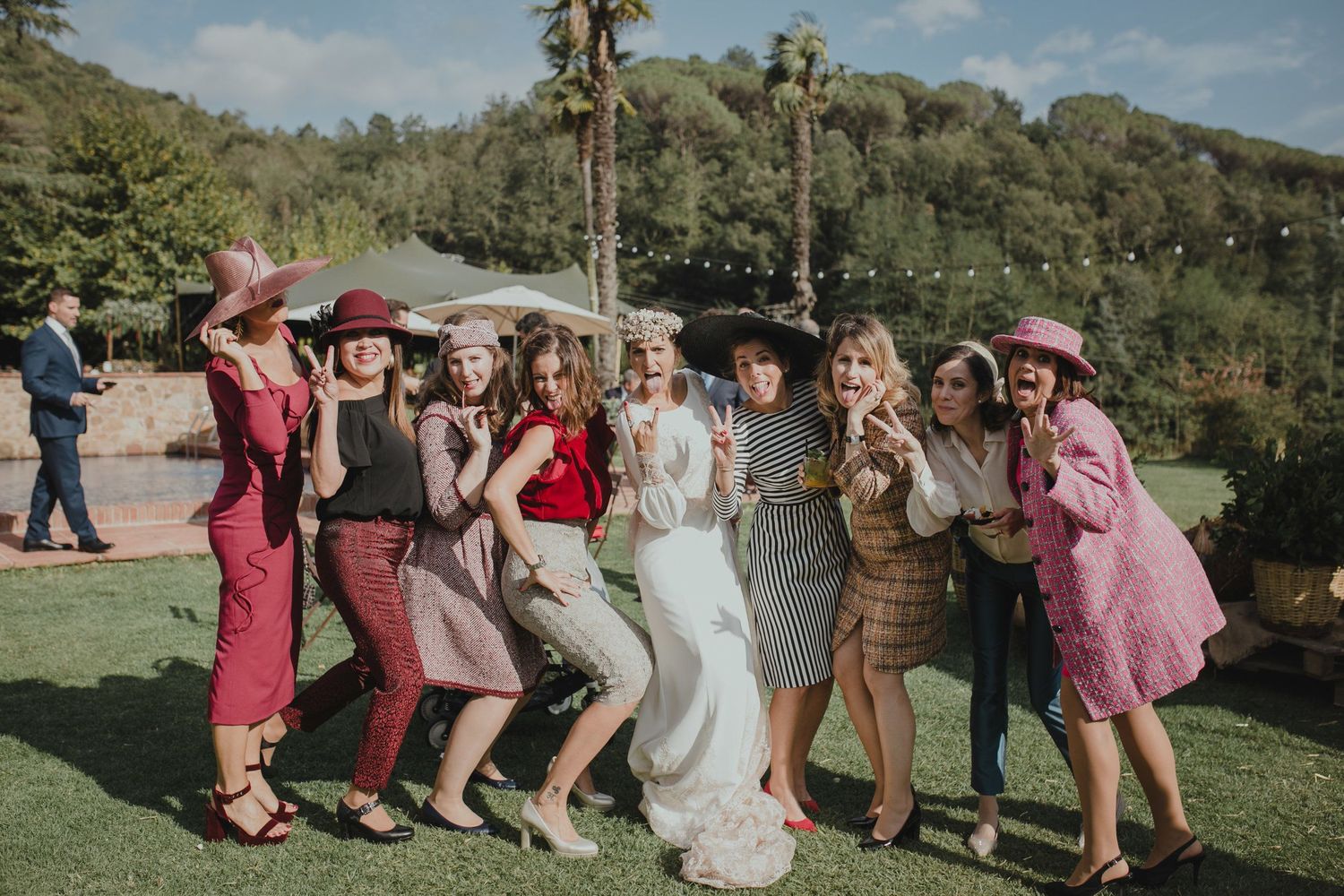 A group celebrating at an outdoor wedding wearing colorful vintage-inspired dresses.