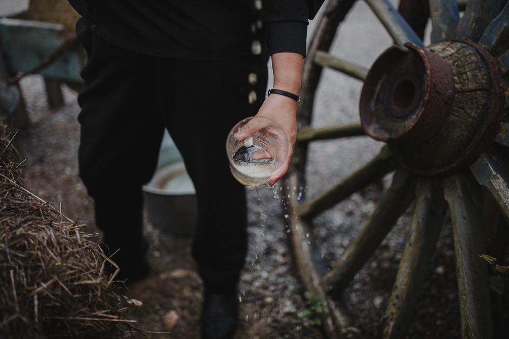 A close-up shot of hands holding a vintage pocket watch near an antique wagon wheel.