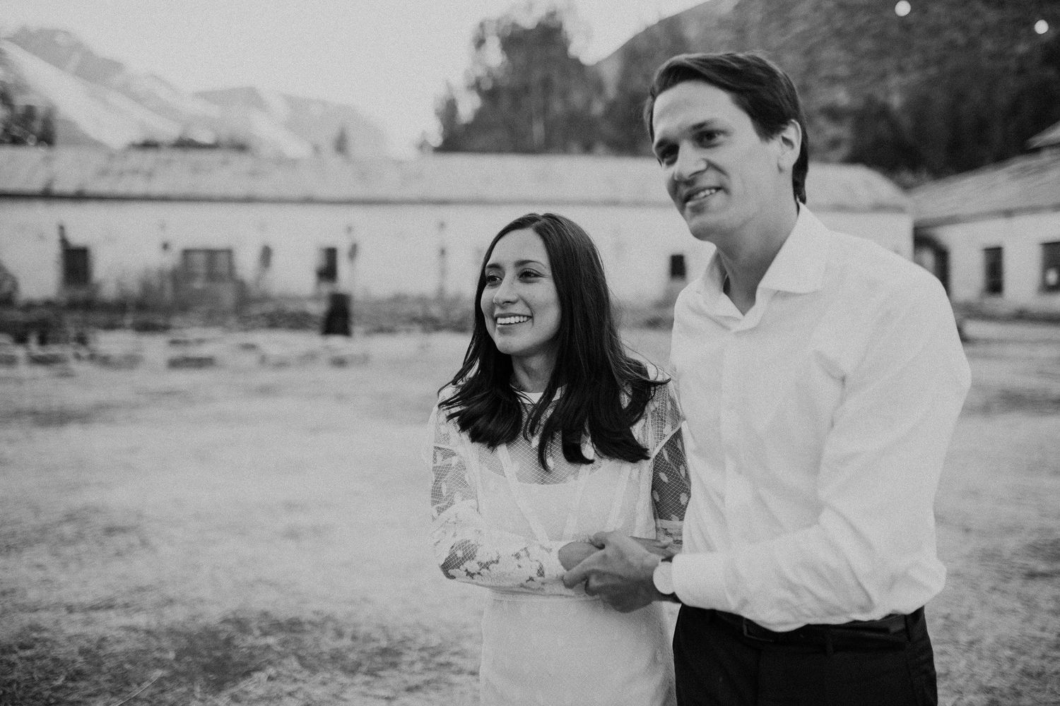 A joyful black and white portrait of a couple laughing together in an outdoor courtyard setting.