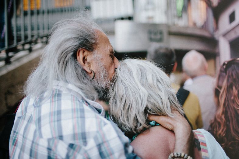 Two elderly people embracing on a crowded street.