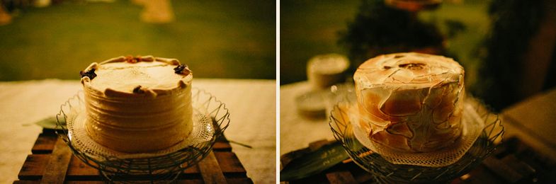Two wedding cakes displayed on rustic stands in warm lighting.
