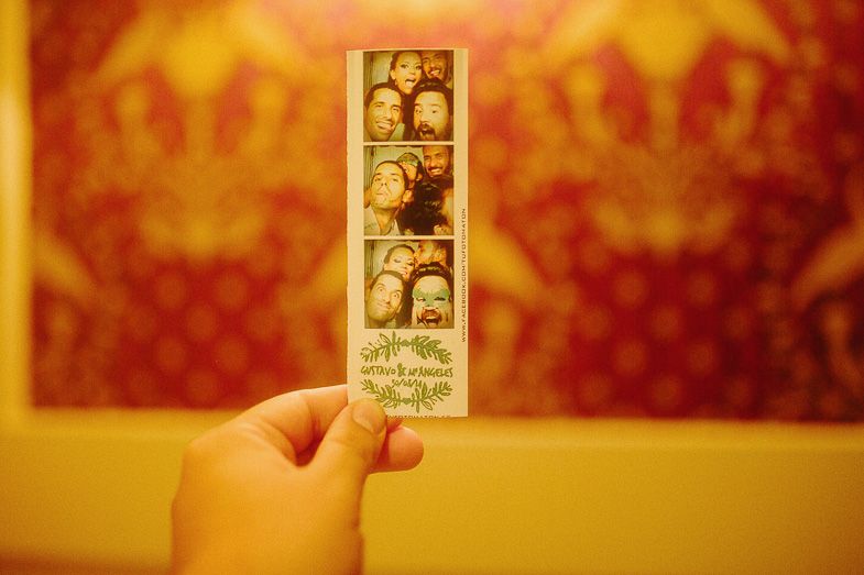 Hand holding a vintage photo booth strip with warm sepia tones in the background.