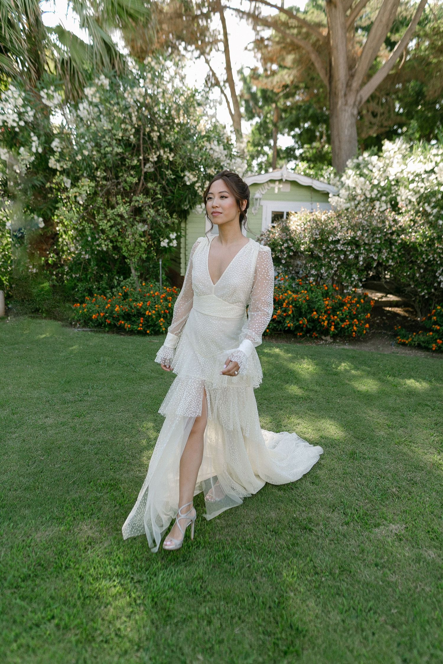 Elegant white dress flows across garden lawn during outdoor bridal portrait session.
