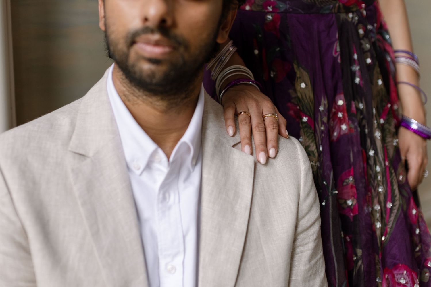 Close detail of Elina’s hand on Jag’s shoulder and the embroidery of her purple outfit.