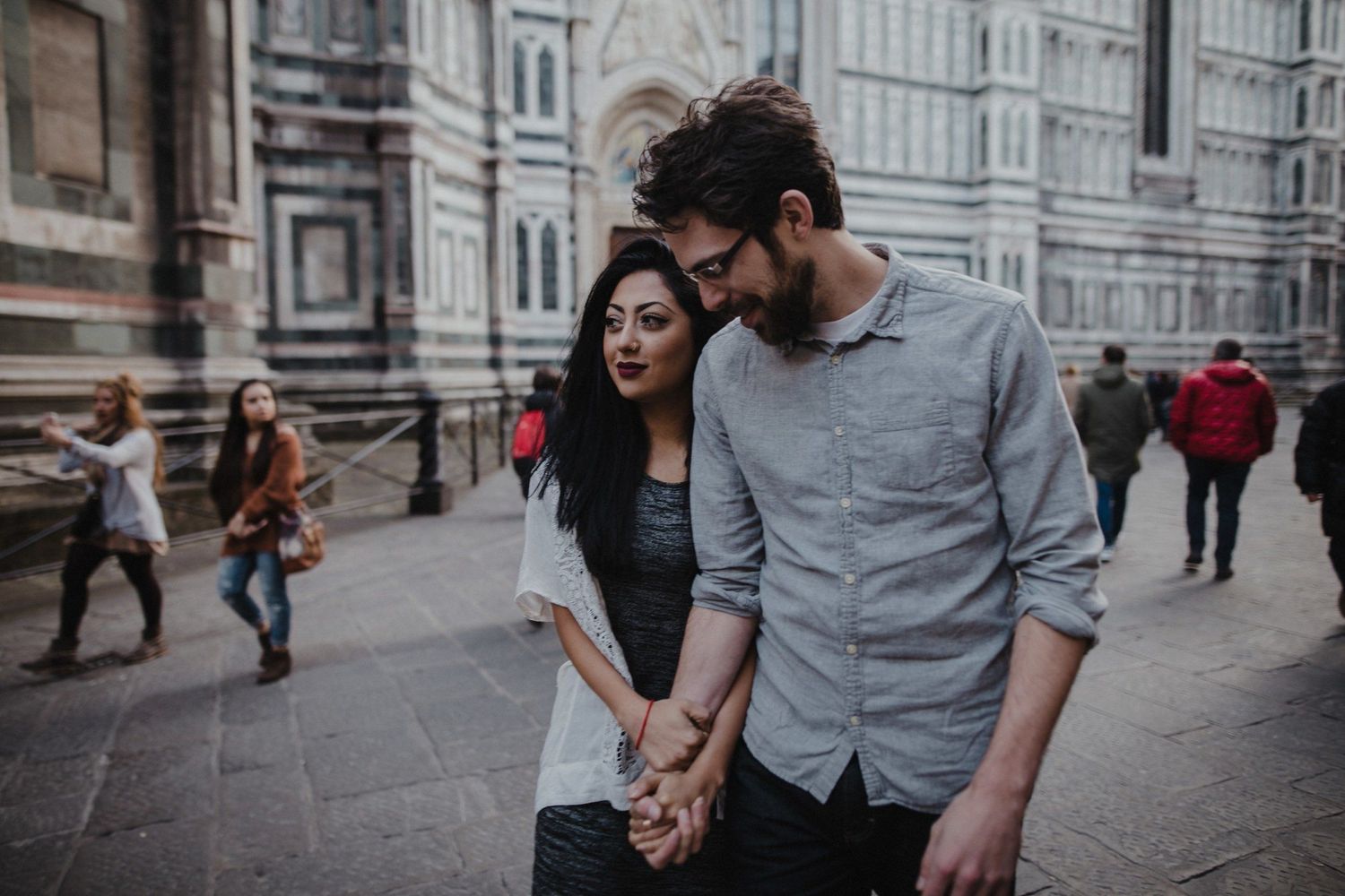 Couple walking together on historic European street with historic architecture in background.