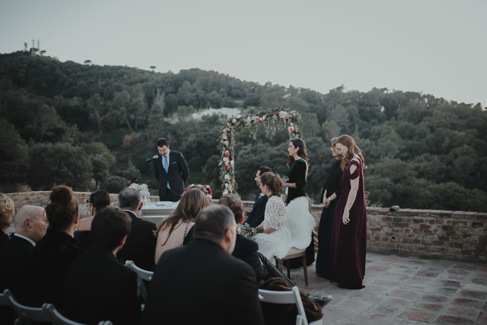 Outdoor wedding ceremony with mountain backdrop and floral arch.