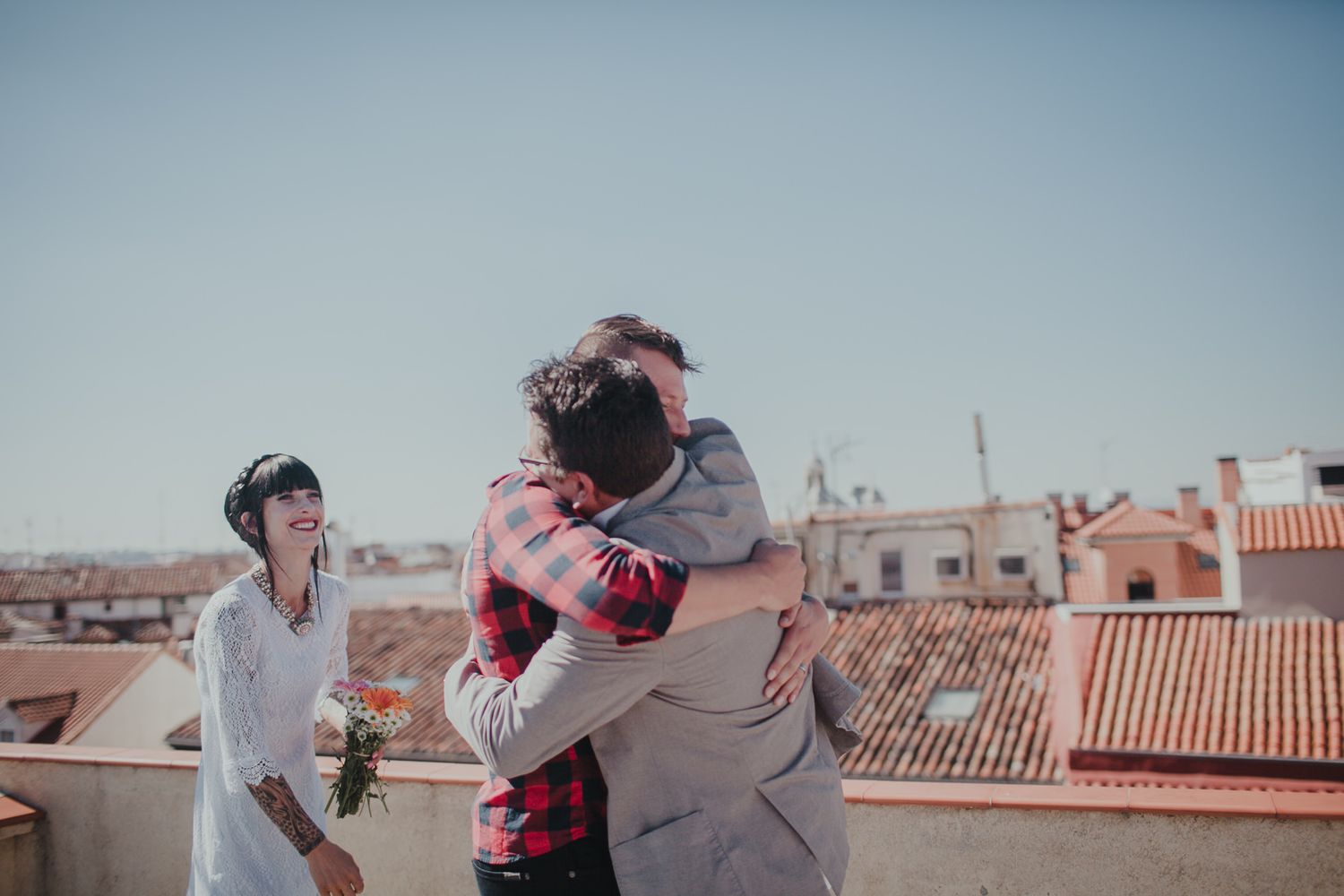A joyful celebration moment on a sunlit rooftop with urban architecture in the background.