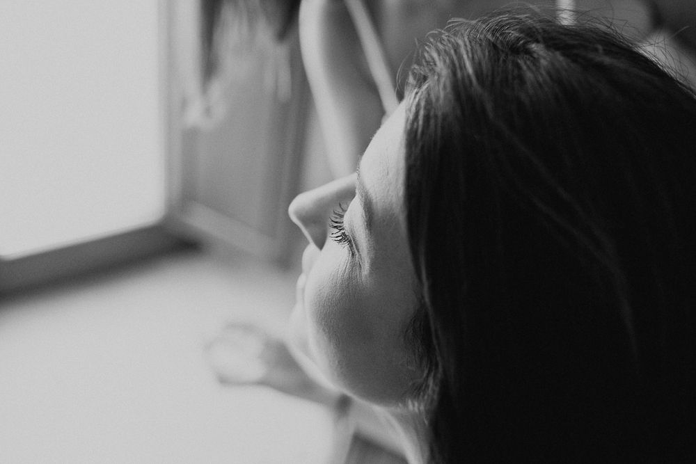 Black and white profile silhouette gazing toward window light.