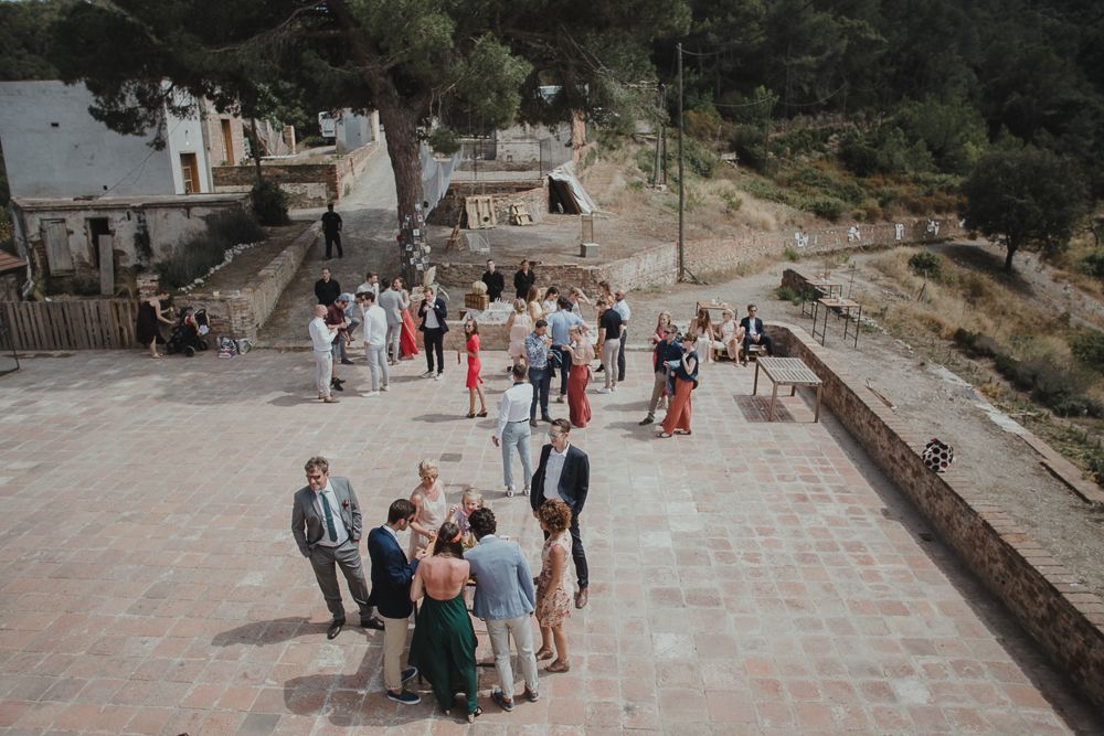 Wedding guests gathering on a stone terrace with mountain views in the background.