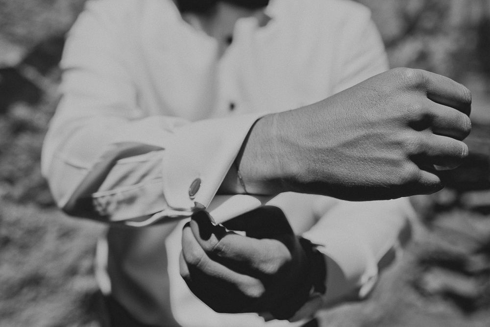 Close-up black and white shot of hands adjusting formal shirt cuffs.