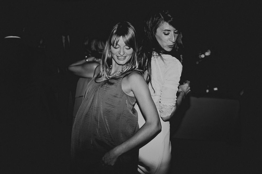 Two guests dancing together at dimly lit wedding reception party.