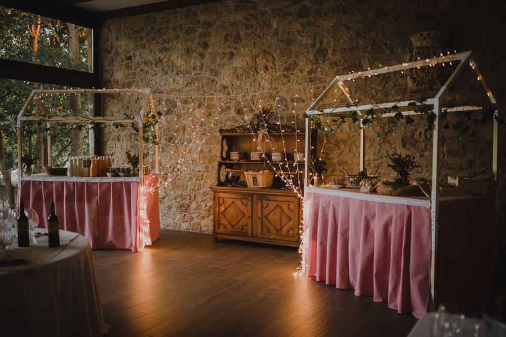 Wedding reception venue with pink tablecloths and rustic wooden arch decorations.
