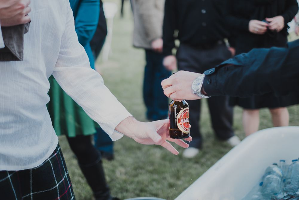 Hands reaching for beverages being served at an outdoor reception.