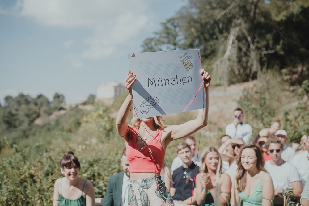 Outdoor wedding guests watch as someone holds up a 