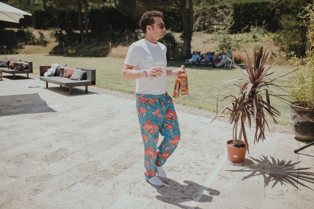 Person in floral print pants and white t-shirt enjoying a sunny outdoor party.