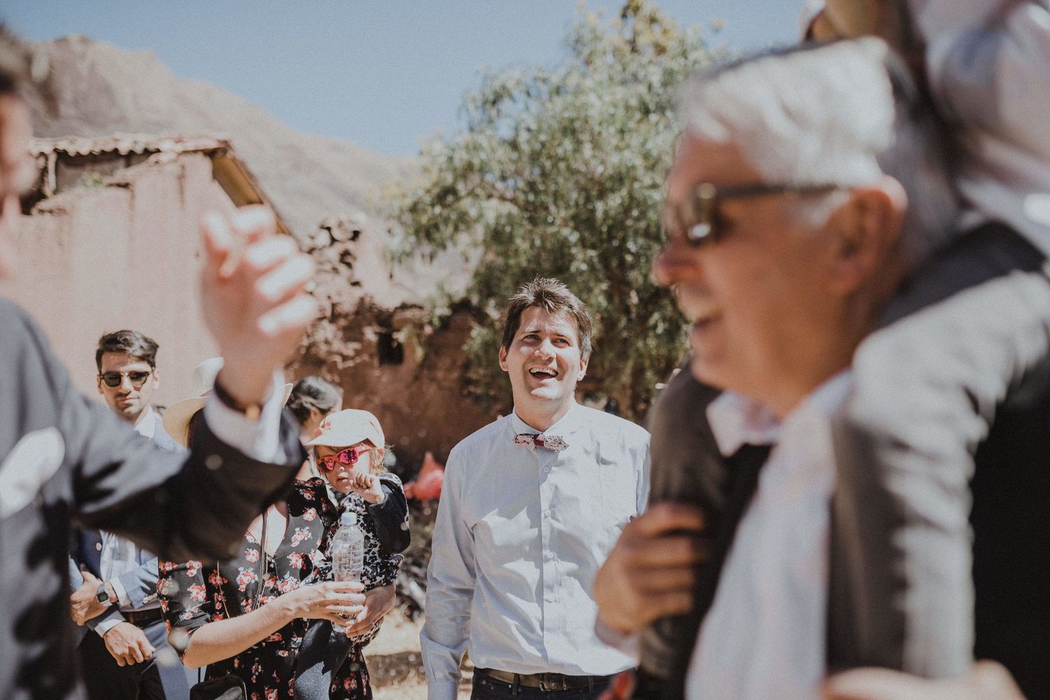 A joyful outdoor celebration with guests gathered in bright sunlight.