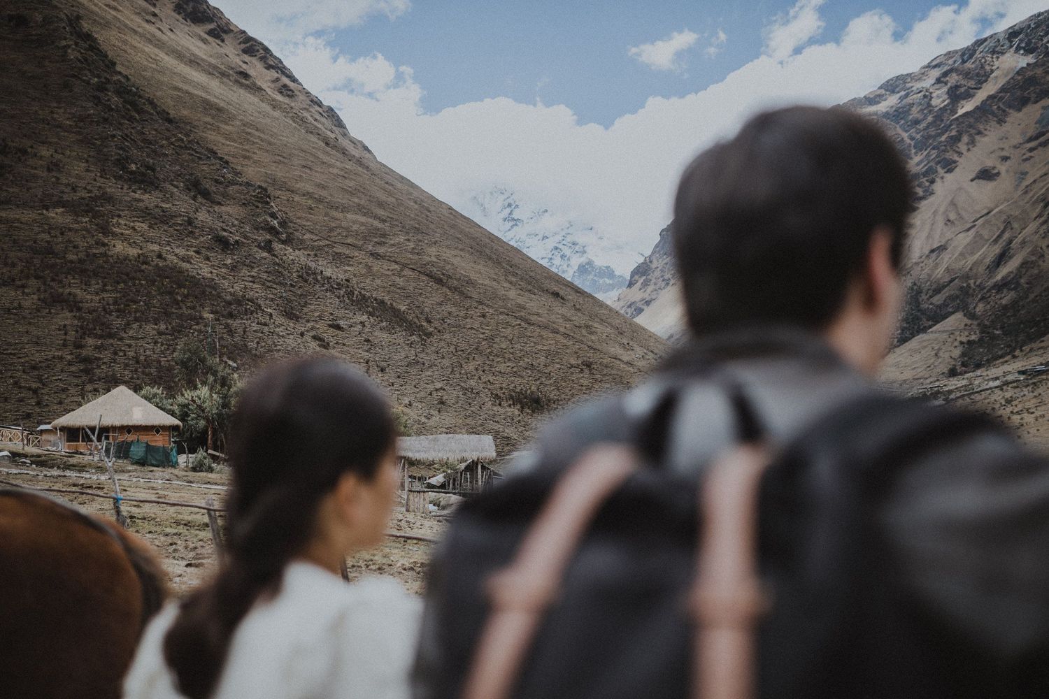 Two adventurers gaze at mountain landscapes while trekking through a remote valley.