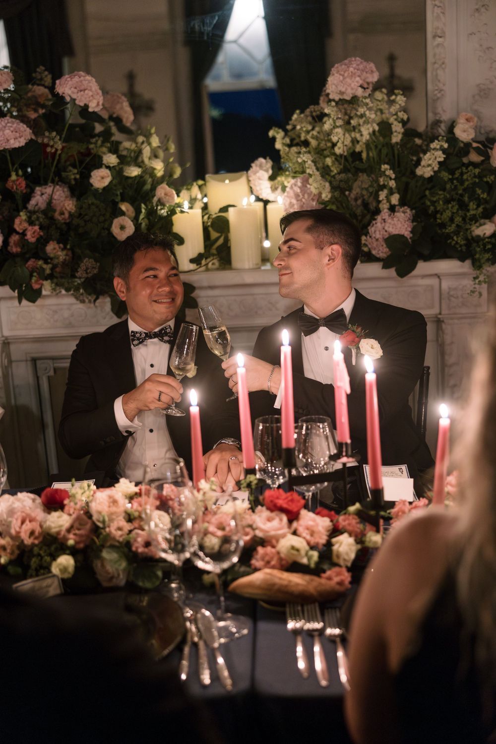 Romantic candlelit dinner table decorated with pink flowers and glowing candles creating an intimate atmosphere.