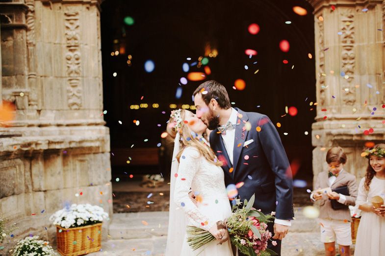 Wedding celebration with colorful confetti and stone architecture backdrop.
