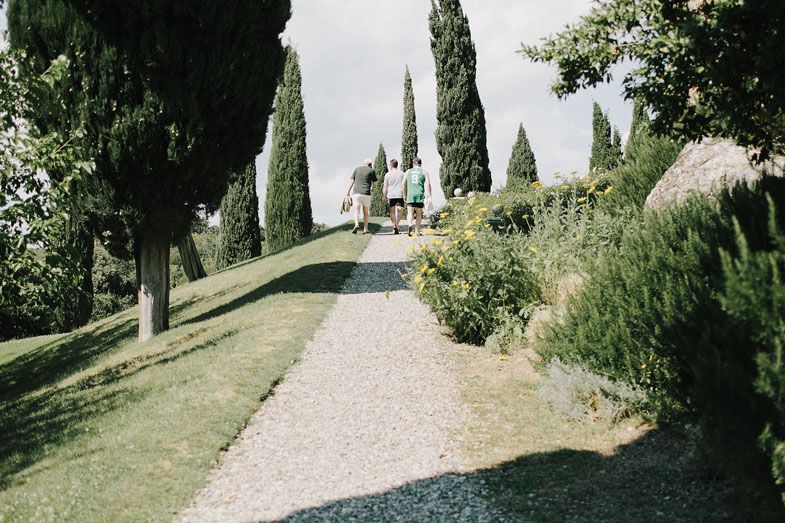 A scenic path lined with cypress trees leads to a charming villa in Tuscany.
