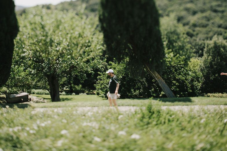 Figure walking through a lush green garden with mountainous backdrop.