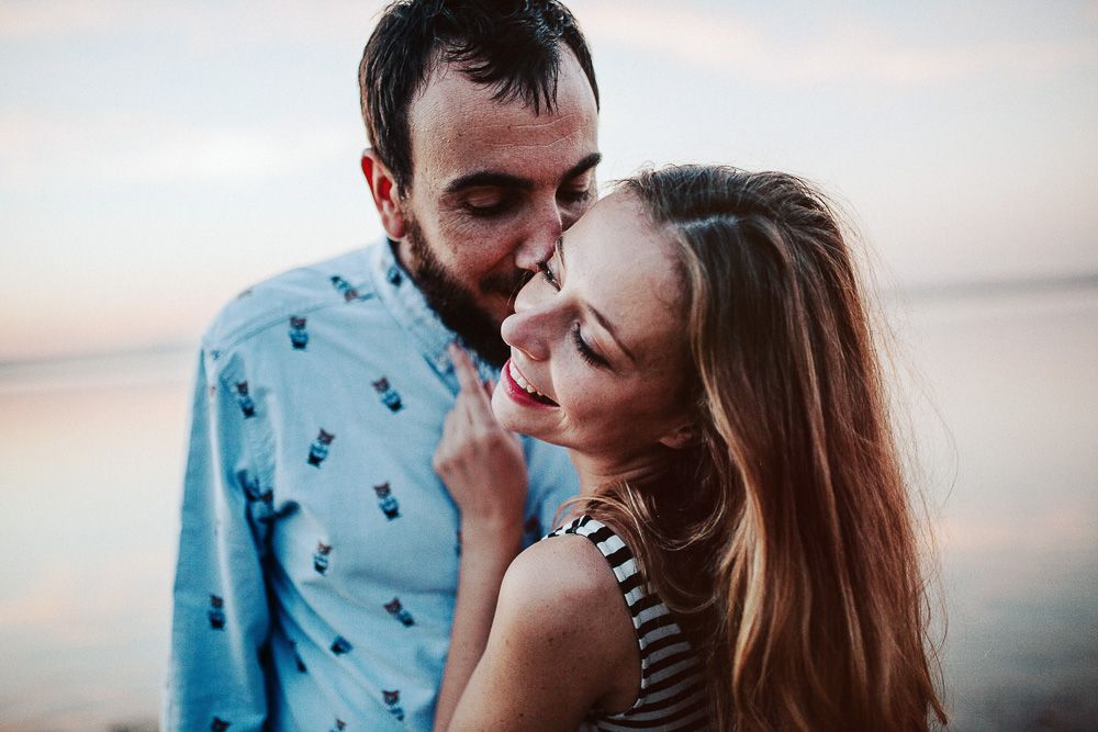 Couple sharing tender moment by lake during sunset photoshoot.