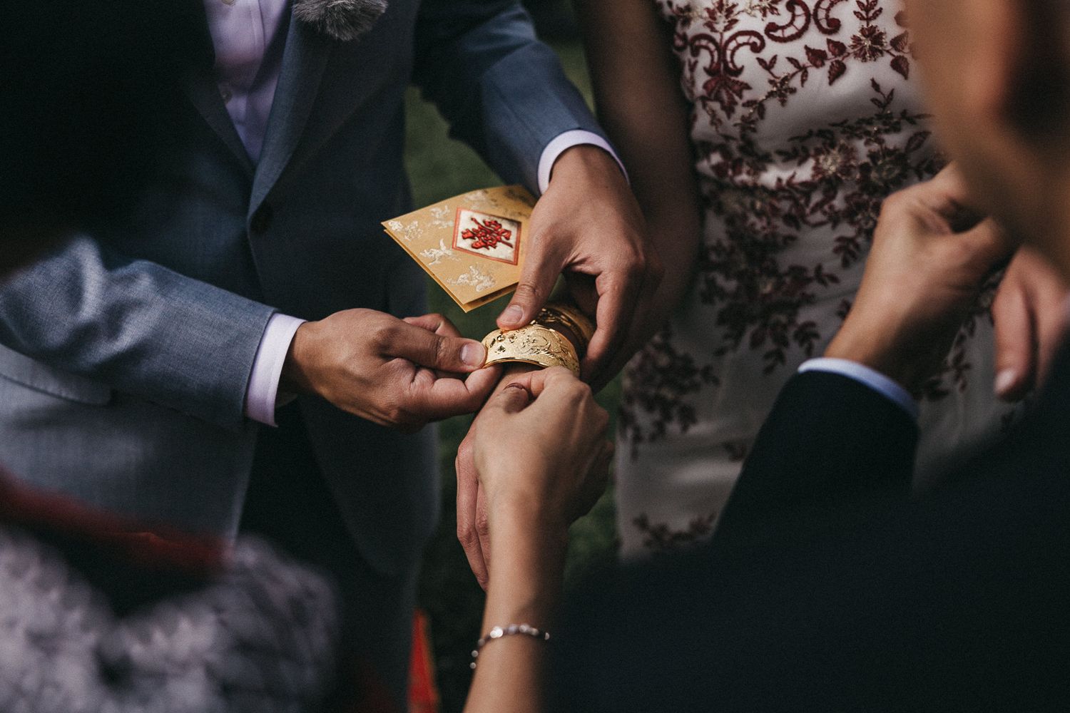 Hands exchanging gold invitation card at formal event.