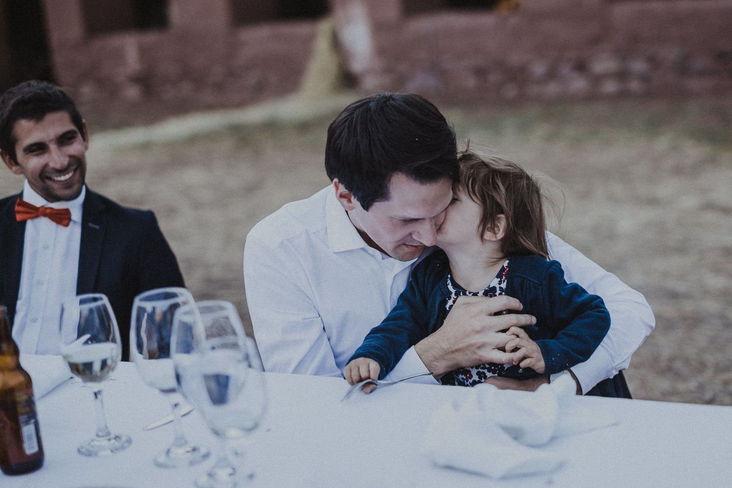 Intimate moment shared at wedding reception table with wine glasses.