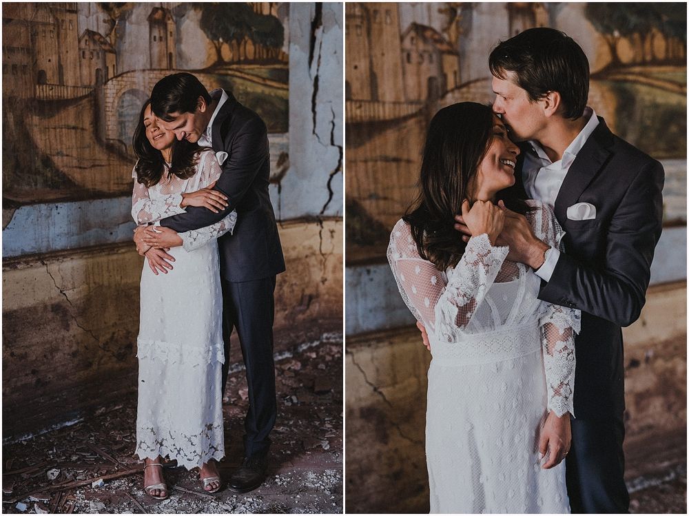 A romantic wedding couple sharing intimate moments against a rustic wall backdrop.