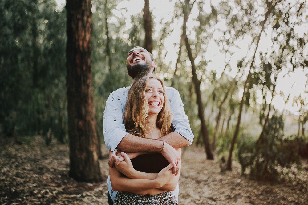 A couple sharing a joyful moment together outdoors in a wooded setting.