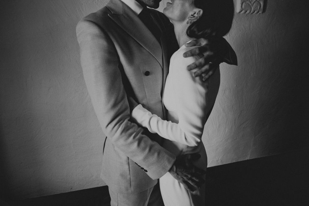 Intimate black and white portrait of couple embracing in formal attire.