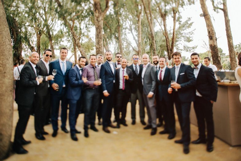 Group photo of formally dressed people gathered outdoors among eucalyptus trees.