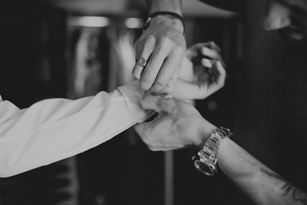 Black and white photo of hands clasped together showing rings and watches.