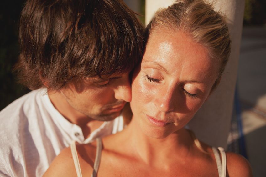 Intimate close-up of couple sharing tender moment in warm lighting.