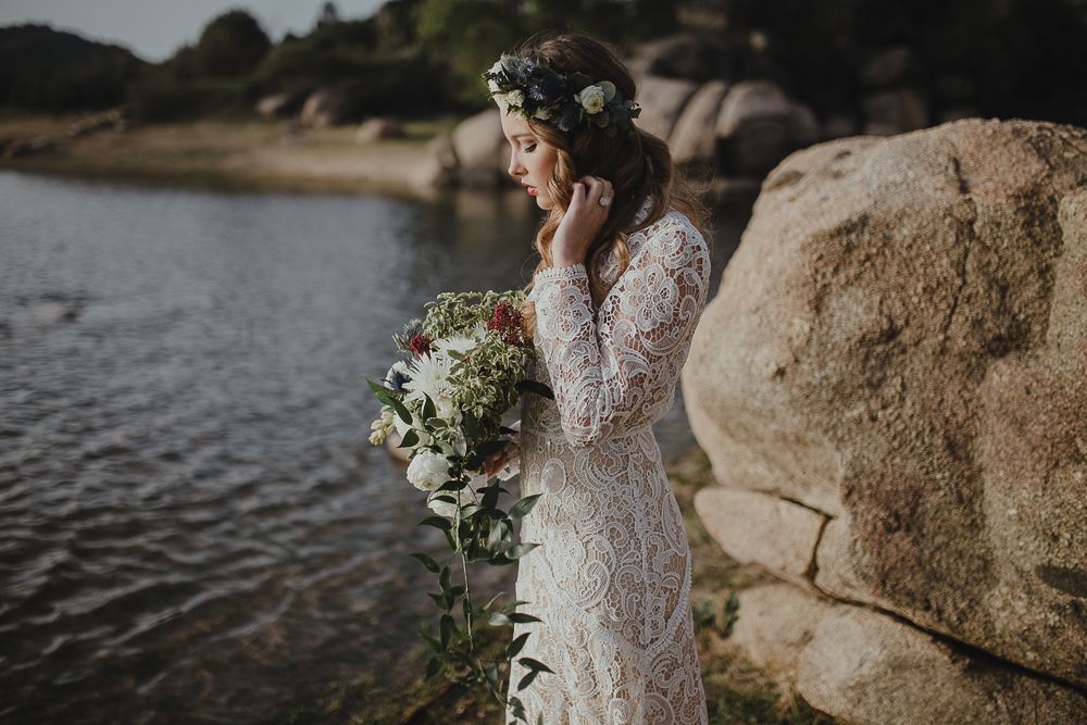 Floral bouquet and lace dress detail against rocky lakeside setting.