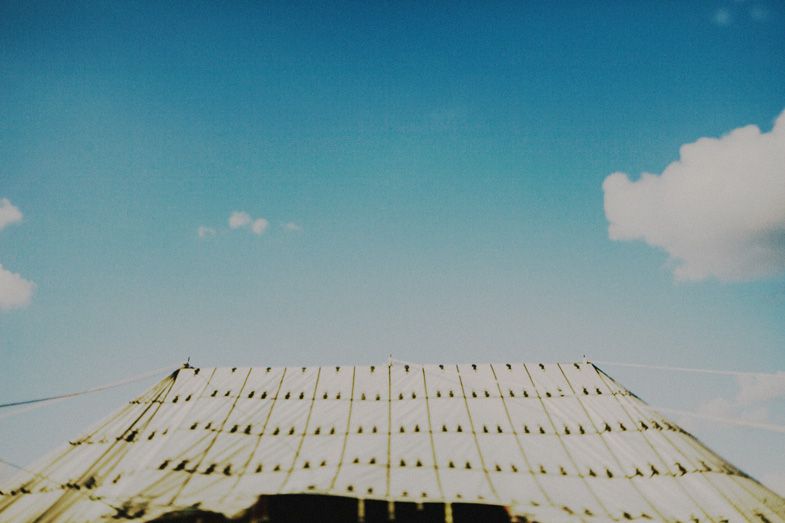 Abstract upward view of geometric patterns against bright blue sky with white clouds.