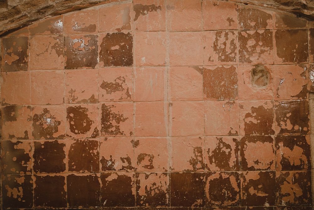 Weathered terracotta colored brick wall with peeling paint texture.