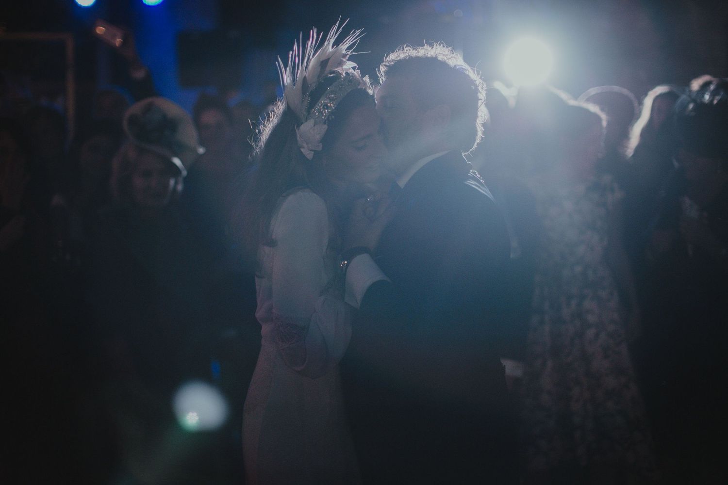 Silhouetted couple dancing surrounded by atmospheric lighting at evening reception.