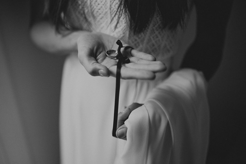 Black and white image of hands holding an antique key against a white dress.