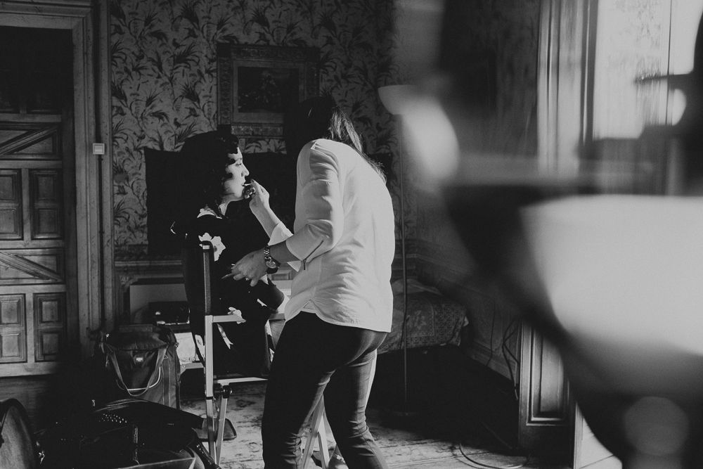 Photographer capturing shots in a room with vintage wallpaper and natural lighting.