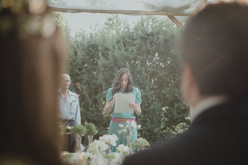 Outdoor wedding ceremony with guests watching couple exchange vows under floral decor.