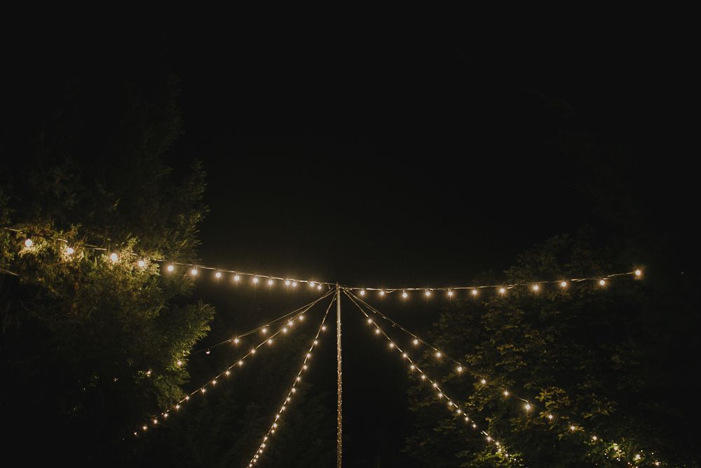 String lights create a magical ambiance as they hang overhead at an outdoor evening event.